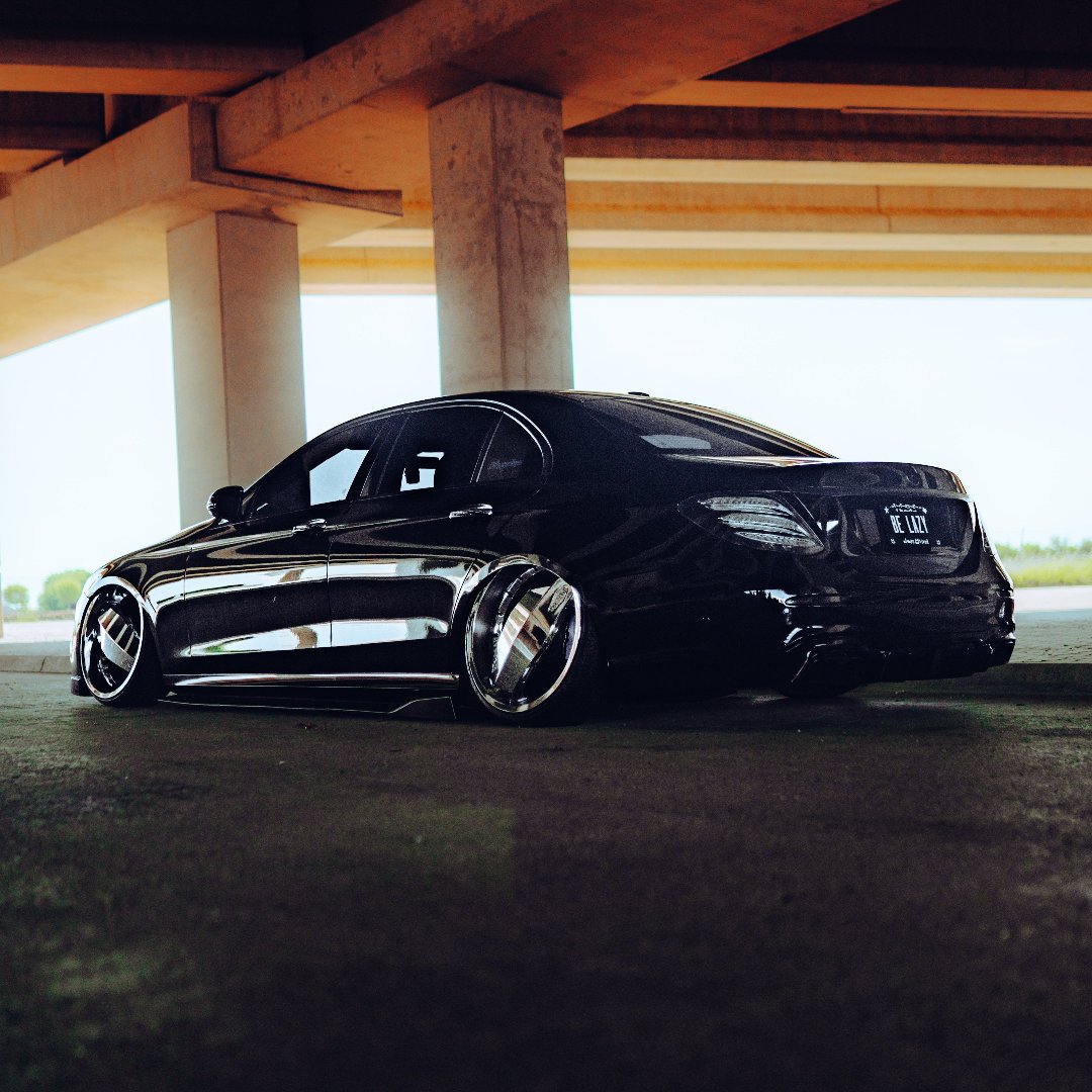 Mercedes E-Class enhanced with gloss black vinyl wrap, featuring air suspension and stylish blade wheels, showcasing a modern and luxurious look.