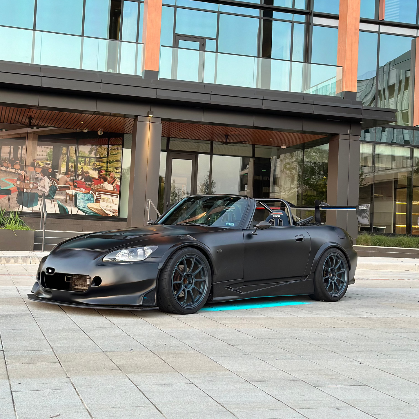 Front and side view of a Honda S2000 wrapped in satin black vinyl, highlighting the sleek contours and distinctive styling of the vehicle.